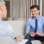 The Benefits of Working with an Ethical Debt Collector A smiling businessman in a blue suit and shirt receives advice from an ethical debt collector