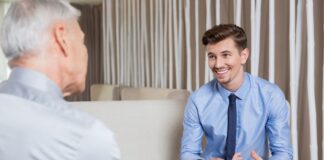 A smiling businessman in a blue suit and shirt receives advice from an ethical debt collector