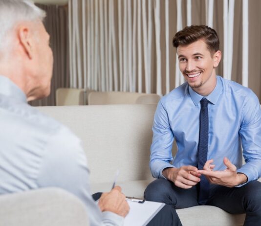 A smiling businessman in a blue suit and shirt receives advice from an ethical debt collector